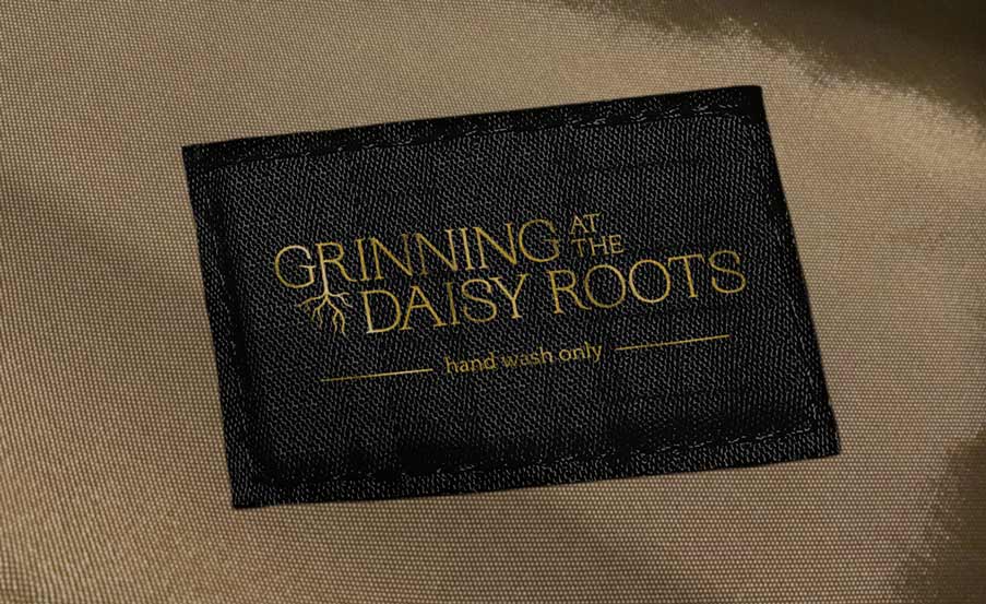 printed fabric label with grinning at the daisy roots logo and text reading hand wash only